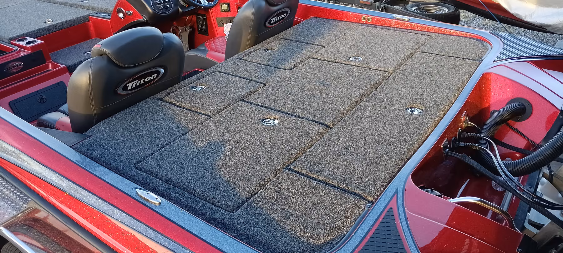 Rear deck and seats of a red Triton bass boat with new charcoal carpet, seats reinstalled either side