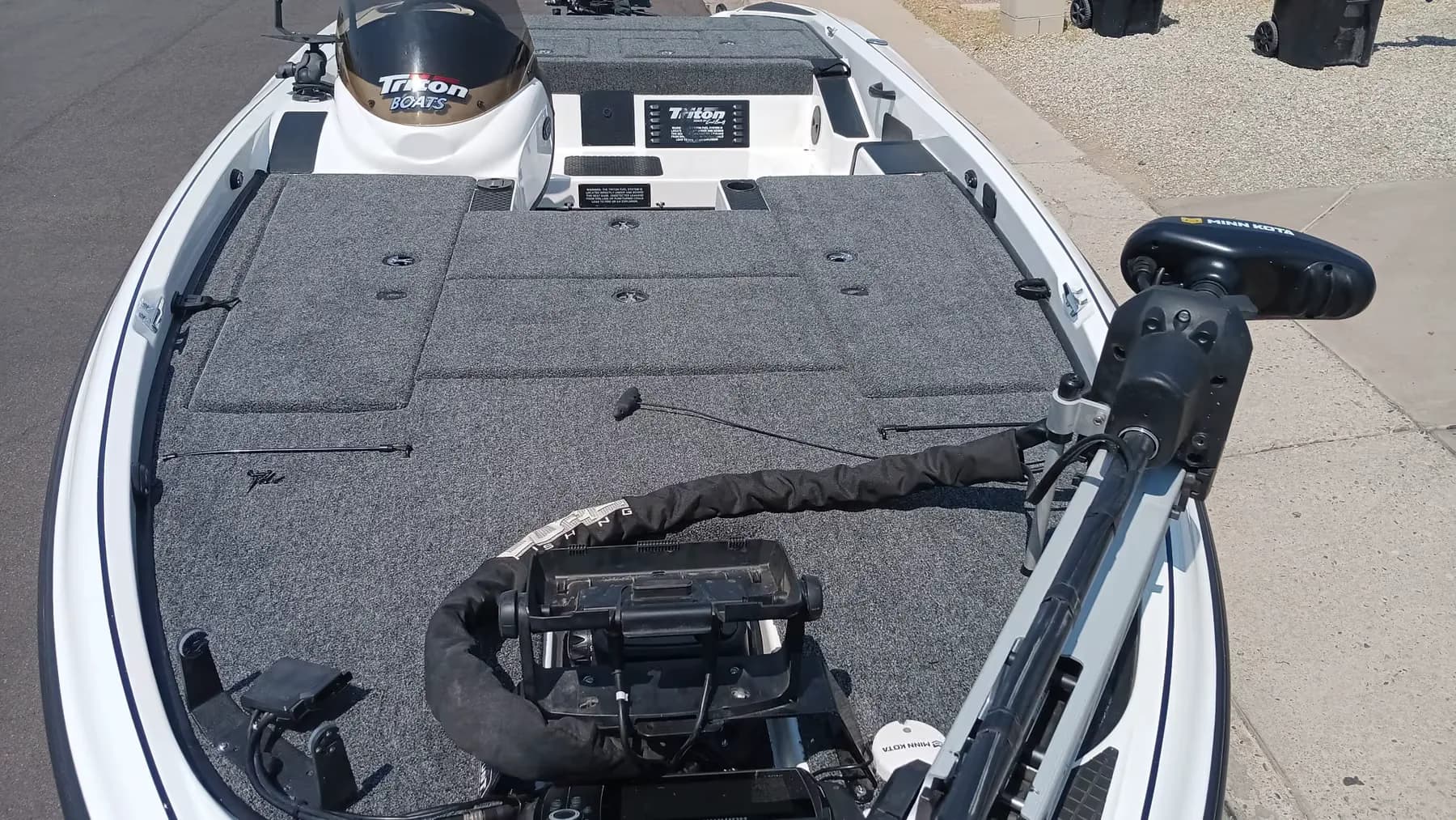 Bow-to-stern view of a white Triton bass boat with a Minn Kota trolling motor mounted and stowed on the front deck