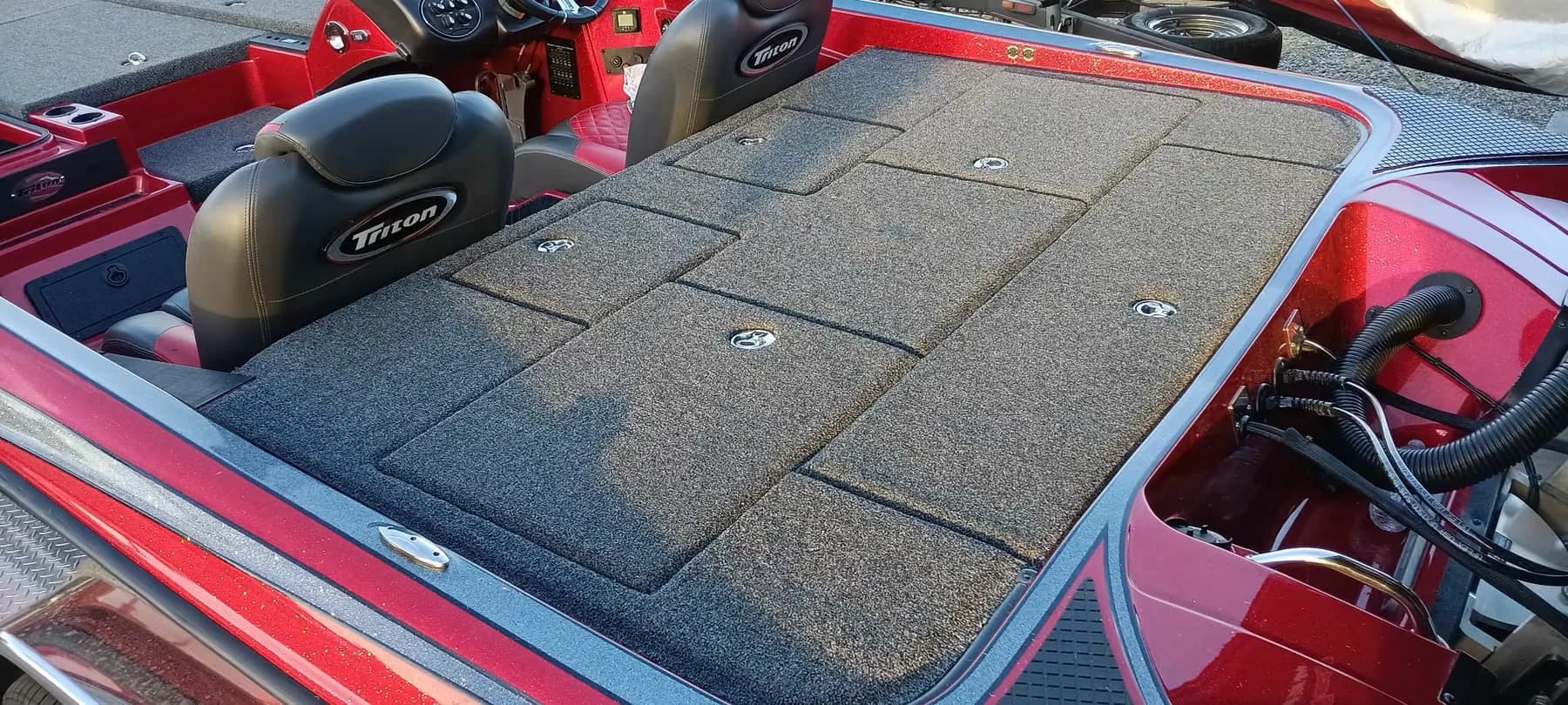 Rear deck and seats of a red Triton bass boat with new charcoal carpet, seats reinstalled either side